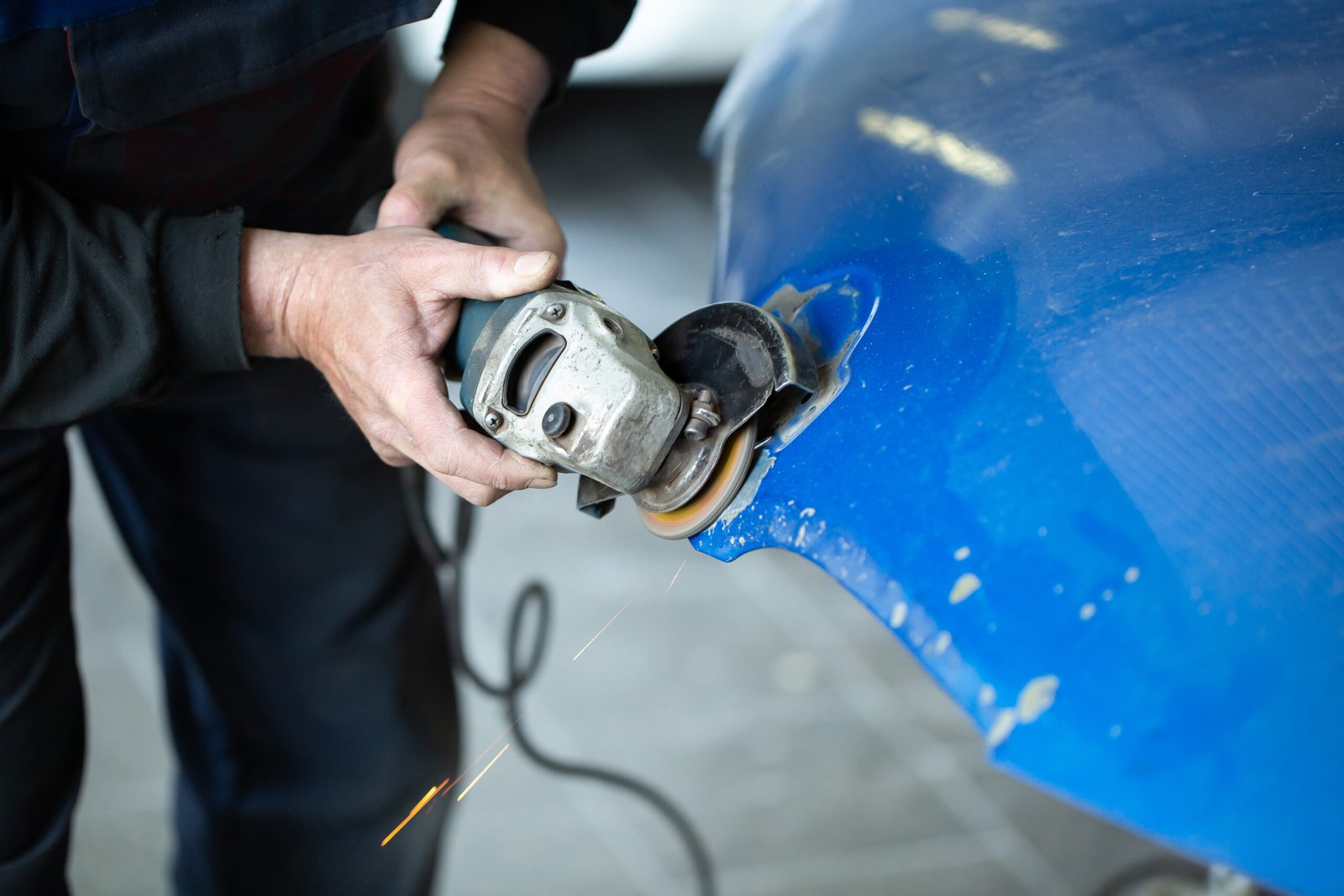 Technician preparing a damaged body panel for repair and paint